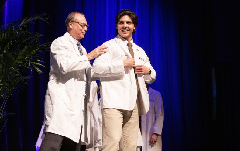 Omar Avila smiles after receiving his white coat from Jeff Balser, MD, PhD. (photo by Erin O. Smith)