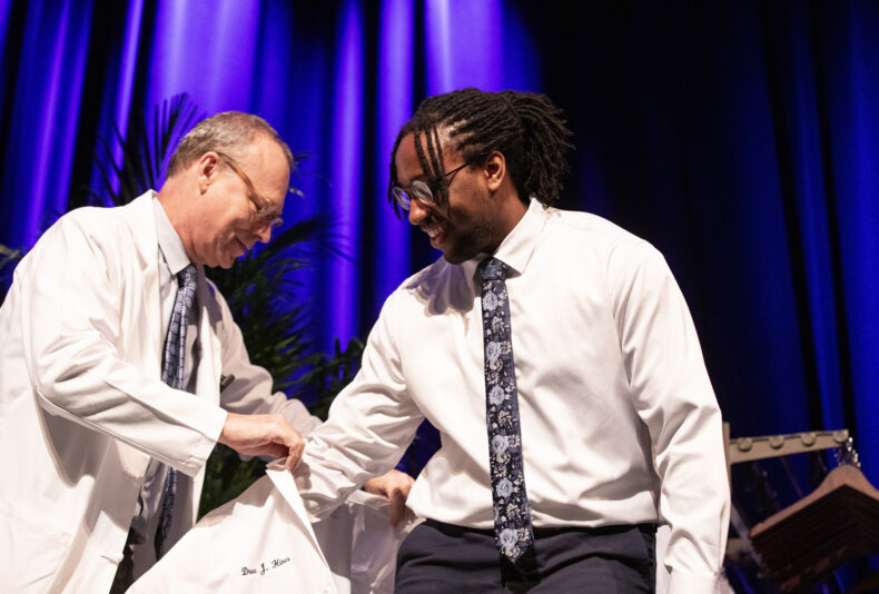 Drew Hines receives his white coat from Jeff Balser, MD, PhD. (photo by Erin O. Smith)