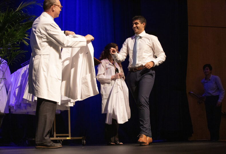 Zayn Kayali gets ready to receive his white coat from Jeff Balser, MD, PhD. (photo by Erin O. Smith)