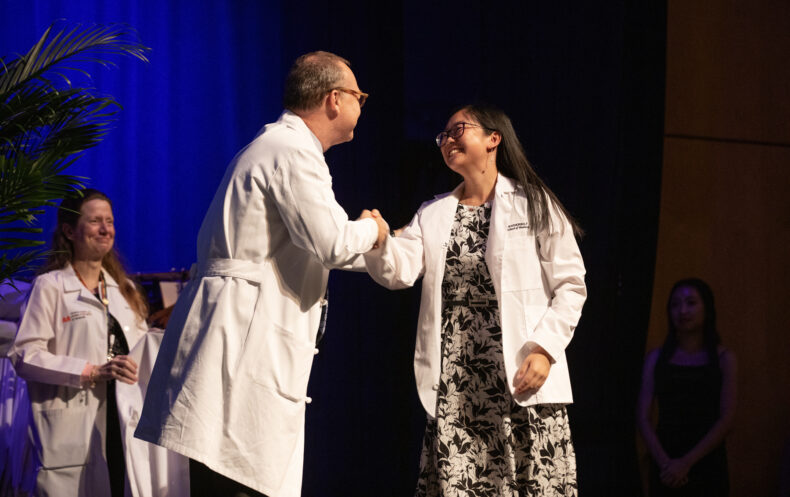 Andrea Zoey Liu shakes hands with Jeff Balser, MD, PhD, after receiving her white coat. (photo by Erin O. Smith)