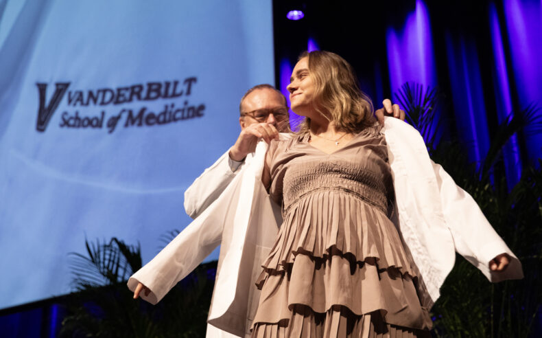 Jeff Balser, MD, PhD, puts a white coat on Madeline Suzanne Fowler during last week’s White Coat Ceremony. (photo by Erin O. Smith)