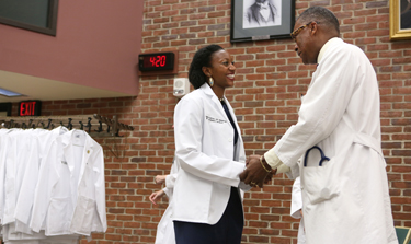 Leah Chisholm is congratulated by Andre Churchwell, M.D., after receiving her white coat. (photo by Anne Rayner)