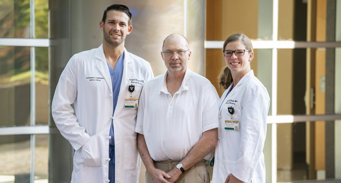 Patient Keith Sanford, center, had a shorter hospital stay and did not take any prescription pain medications after Joseph Broucek, MD, and Meredith Duke, MD, performed a minimally invasive, robot-assisted abdominal hernia repair. 