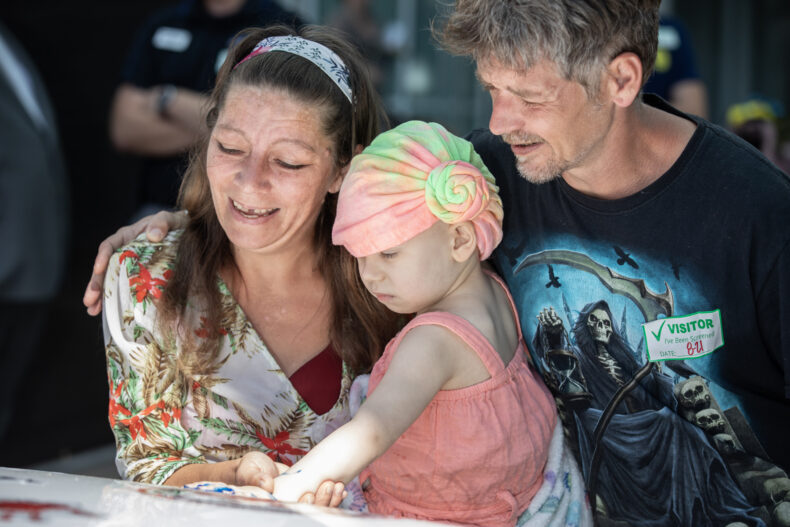 Savannah Shultz and C.J. Whitman help their 3-year-old daughter, Stella Shultz, put her handprint on the car. (photo by Erin O. Smith)