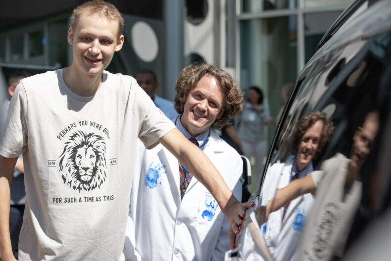 Warren DeGraff III, 16, puts a handprint on the car while Jason Schwartz, MD, PhD, looks on. (photo by Erin O. Smith)