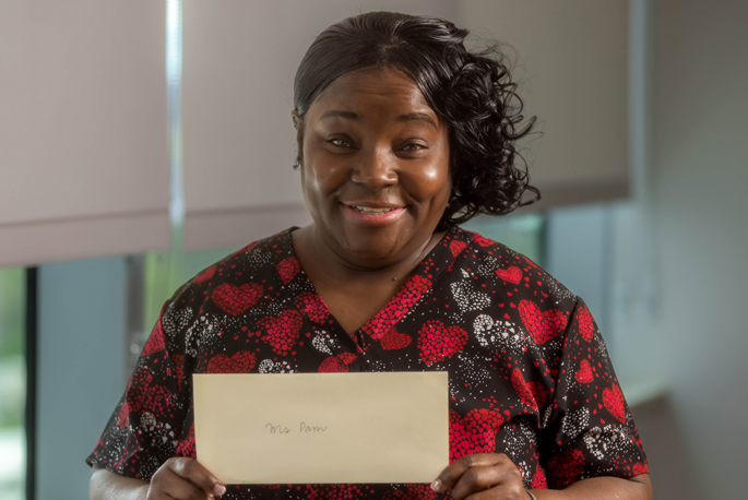 Patient care technician Pamela Spencer holds up a handwritten letter from a patient’s parent filled with praise for Spencer’s special bond with her patients.