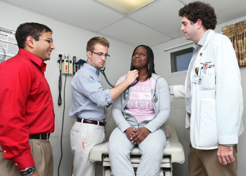 VUSM leadership soon realized the introduction to hands-on patient care that Shade Tree Clinic provided was unparalleled. Here, Ravi Patel, Ben Deschner and Shane Magee, left to right, work with patient Tiffany Renee Davis. (photo by Susan Urmy)