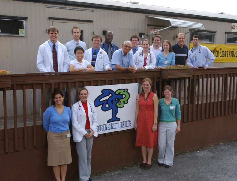 Medical student and faculty volunteers pose outside the first home of Shade Tree Clinic, a shared double-wide trailer just off Dickerson Pike. On either side of the clinic sign are student founders Kristina Collins, MD, on left, and Katie Cox Johnson, MD, on right. 