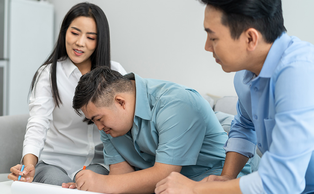 Mom and dad with son with Down syndr ome signing a paper