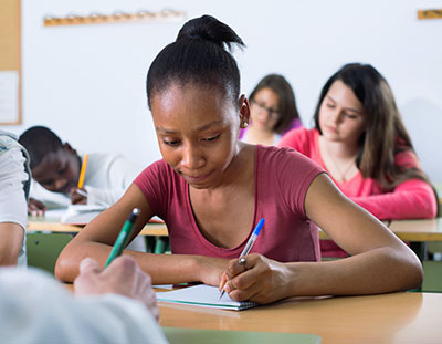student at table writing in notebook