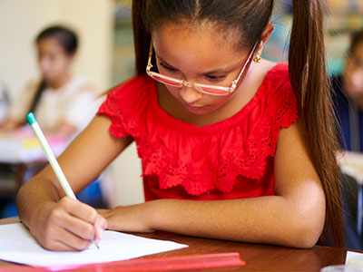 student at table writing in notebook