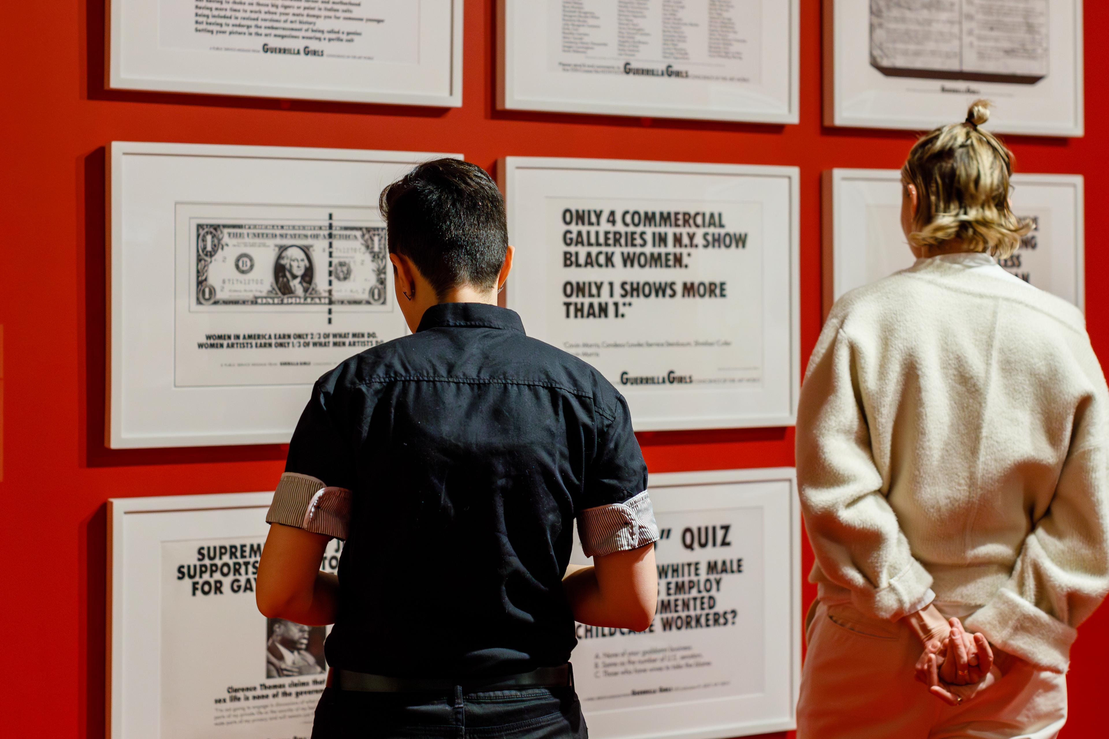 Two people face a gallery wall to look at art