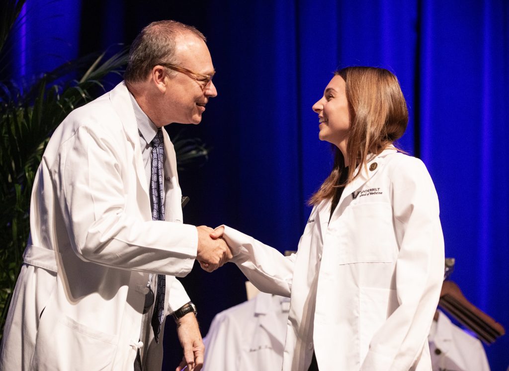 Dean Balser shakes a new medical student's hand during the white coat ceremony.