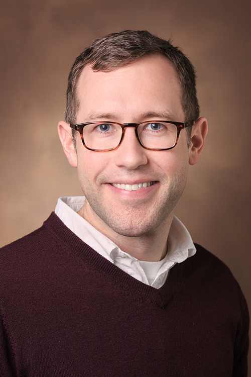 Portrait of Dr. Frank Mason, a white man with glasses in a black sweater