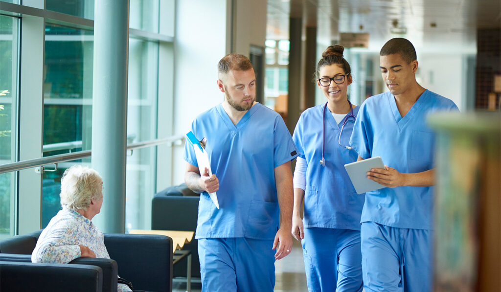 Multiracial group of healthcare workers in blue scrubs walking through a lobby in a hospital