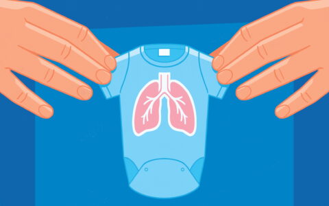Hands holding a tiny onesie with lungs pictured on the front