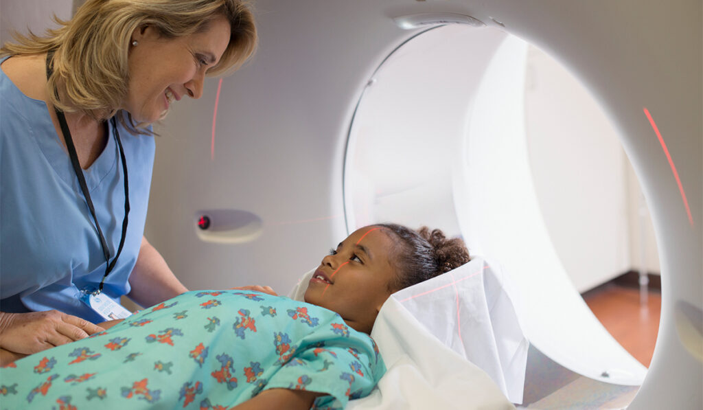 Nurse reassures girl lying down in an MRI machiine