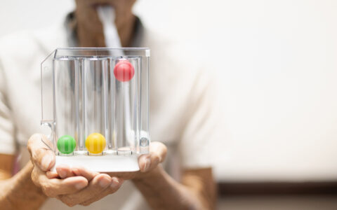 Patient blowing into a tube to measure lung health. There are three balls, green, yellow and red, and the red ball is lifted.