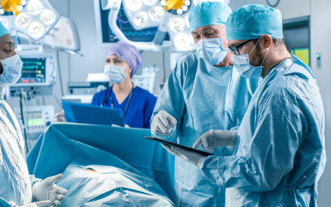 professional surgeons and assistants talk and use digital tablet computer during surgery
