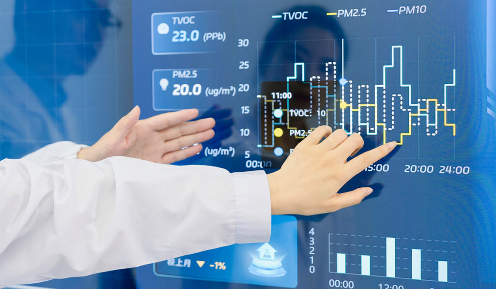 Scientists discussing project data in front of a control screen in the hallway of lab
