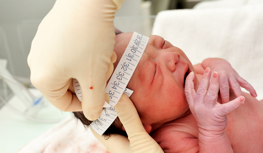 Newborn with head being measured