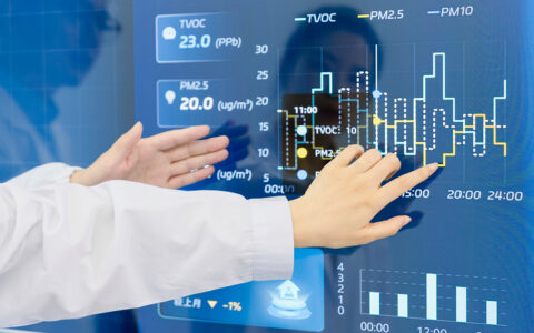 Scientists discussing project data in front of a control screen in the hallway of lab