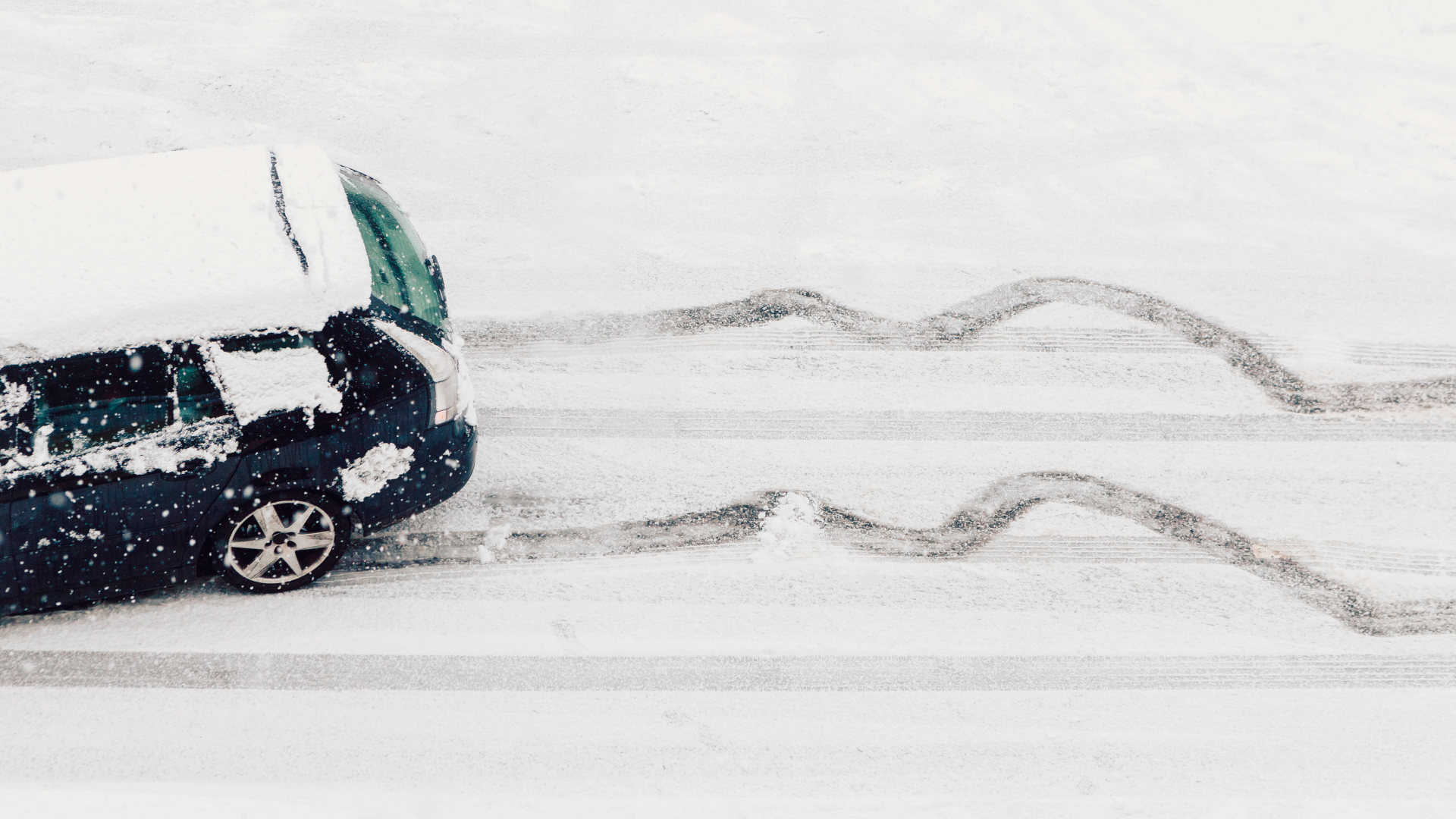 a car swerves on a snow-covered road