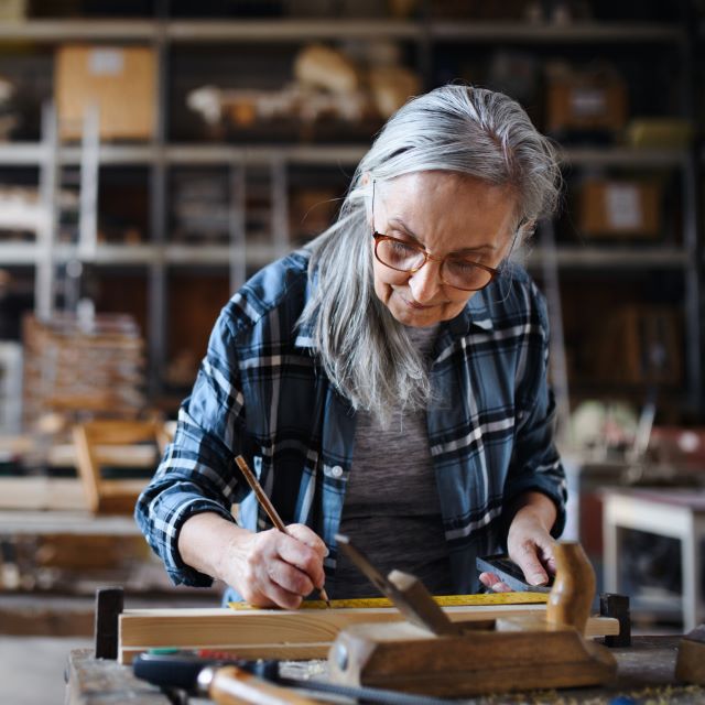 Senior craftswoman working with hand tools in carpentery workshop.