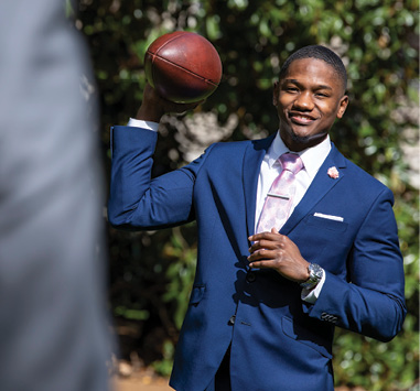 photo of a student in a suit throwing a football