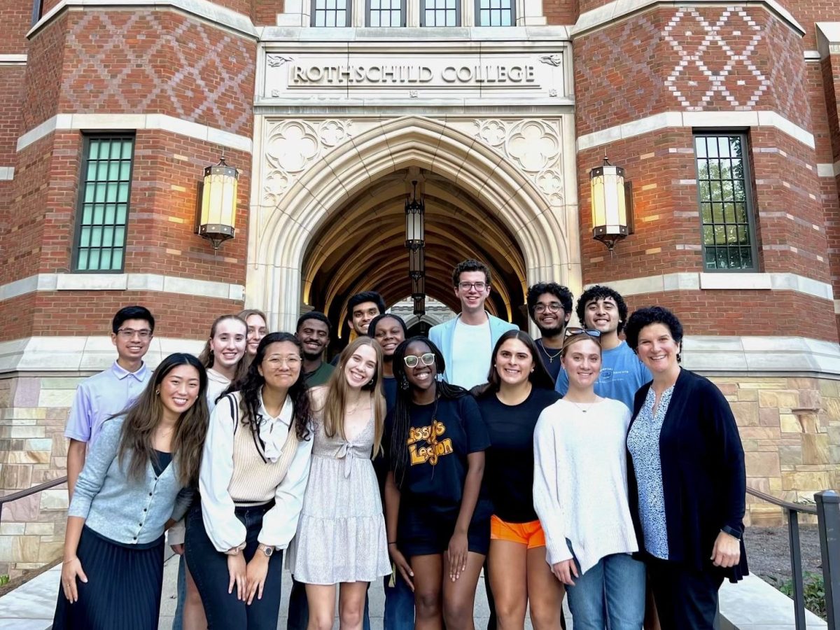 Students and the Academy director pose for a photo in front of Rothschild College.