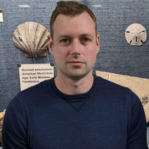 Man smiling in front of fossil display