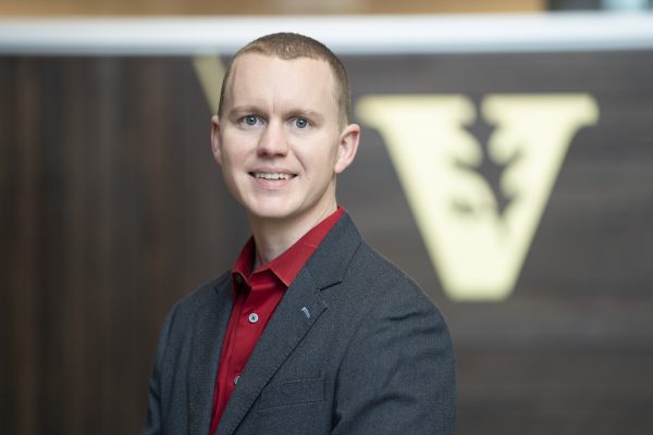 person in red shirt and gray jacket smiling
