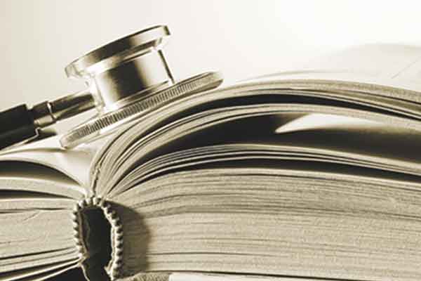 Sepia colored photo of an open book with a stethoscope on the opened pages