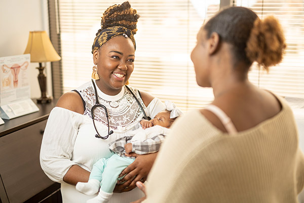 Nurse-Midwife Vernicia Winford holds her infant niece and talks to her sister-in-law