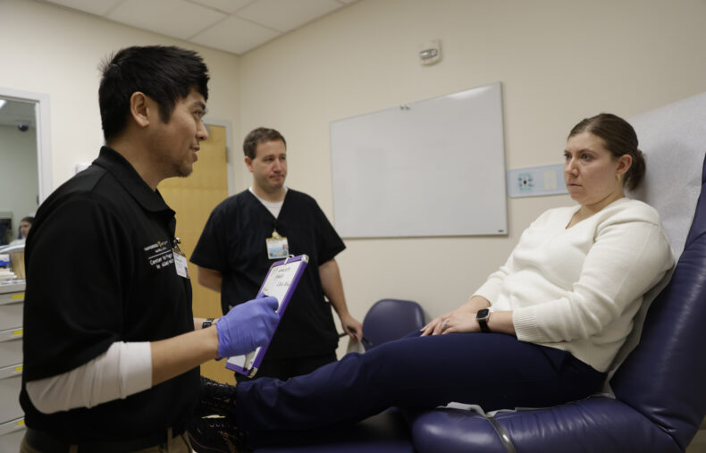 During the training course, Tony Gold, left, goes through the steps to assess a patient for a possible stroke as Mike Moore, RN, SCRN, looks on. Hannah Rohrs is acting as the patient during the session. (photo by Donn Jones)